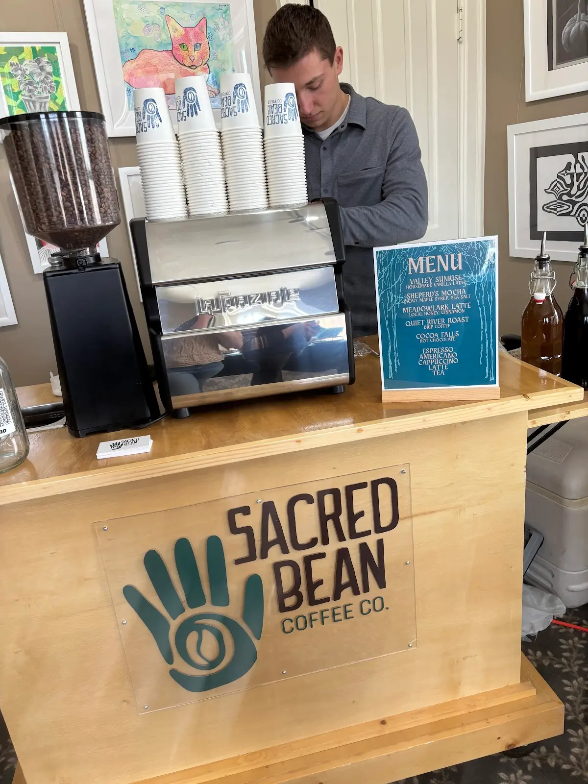 Sacred Bean espresso cart set up indoors with menu display